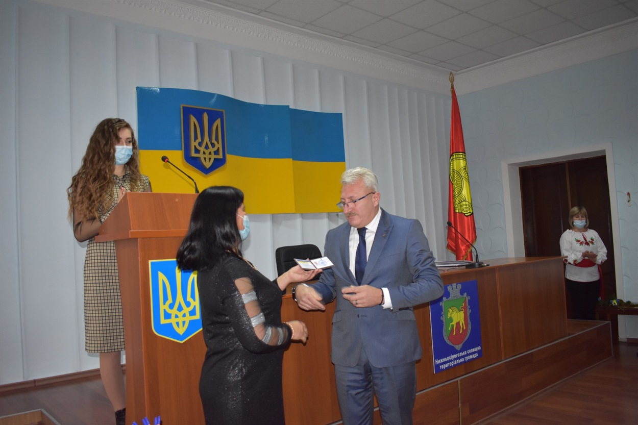 Член Нижньосірогозької ТВК Олена Пономаренко вручає посвідчення Нижньосірогозького селищного голови Дмитру Такаджи