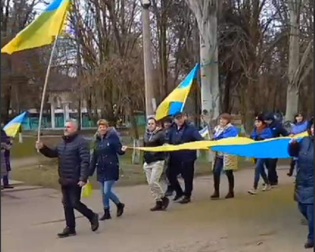 Петро Збаровський попереду колони з прапором, очолює проукраїнський мітинг у Новотроїцькому на початку березня 2022 року. Фото: скріншот відео